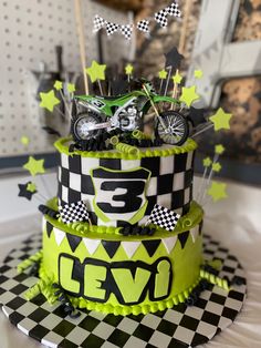 a three tiered cake decorated in green and black with a bike on top that says 3 eleven