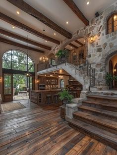 a large open floor plan with wood floors and stone walls, stairs leading to the upper level