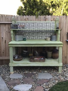 a green shelf sitting on top of a gravel covered ground next to a wooden fence