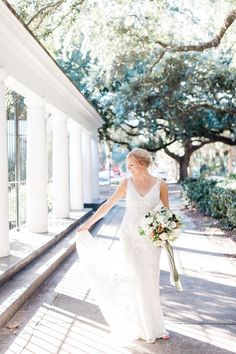 a woman in a wedding dress walking down the street with her hand on her hip