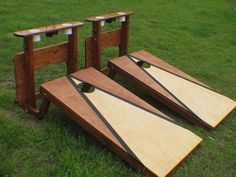 three pieces of wood sitting on top of a grass covered field next to each other