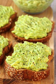 four pieces of bread with guacamole spread on top and sesame seeds in the middle