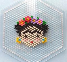 a beaded brooch is sitting on top of a clear plastic holder with beads