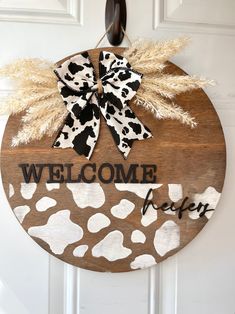 a welcome sign hanging on the front door with an animal print bow and burlock