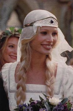 a woman in a wedding dress with long blonde hair and a veil on her head