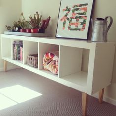 a white shelf with some books and plants on it