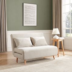 a living room with green walls and a white couch in front of a large window