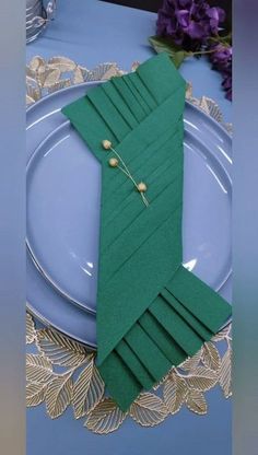 a table setting with green napkins and place settings on it, along with purple flowers