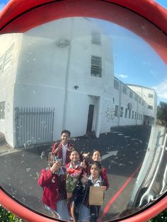 a group of people standing in front of a mirror on the side of a building