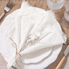 a place setting with white linen napkins and silverware