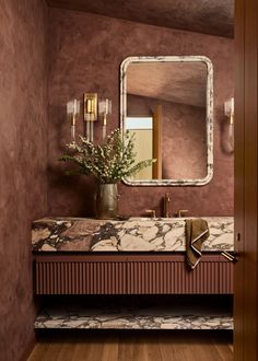 a bathroom with a sink, mirror and flowers on the counter top in front of it