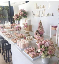 a table with pink flowers and cupcakes on it