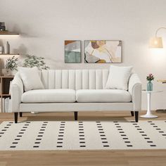 a white couch sitting on top of a wooden floor next to a table and lamp