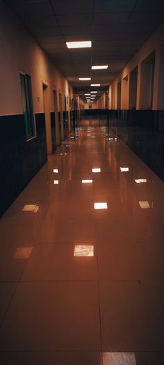 an empty hallway with several windows and lights on either side of the corridor is lit by recessed lighting