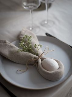 a white plate topped with an egg on top of a table next to two wine glasses