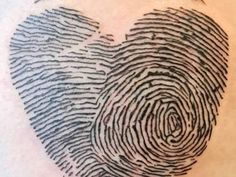 a heart shaped fingerprint tattoo on the back of a woman's shoulder and chest