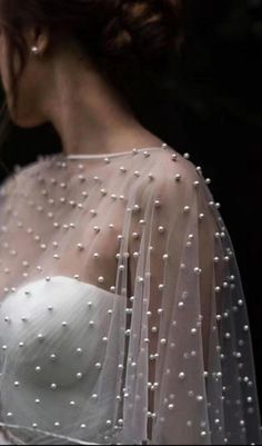 the back of a woman's wedding dress with pearls on it and a veil