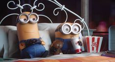 two minion characters sitting on a bed with popcorn