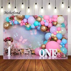 a backdrop with balloons, flowers and butterflies for a one - year birthday party at mehopfond