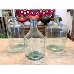 two empty glass bottles sitting on top of a wooden table next to a vase filled with water