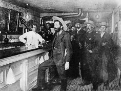 black and white photograph of men in hats at a bar