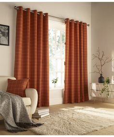 a living room filled with furniture and a large window covered in orange plaid drapes