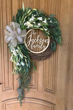 a wreath with the words jackson family on it hanging on a front door in front of a wooden door