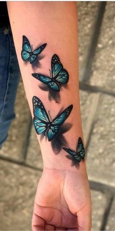 a woman's arm with three blue butterflies on the left side of her wrist