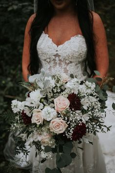 a bride holding her bouquet in the woods