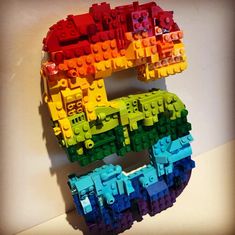 the letter e made out of legos is shown in rainbow colors on a white surface