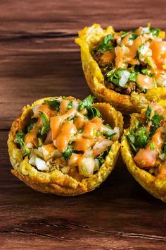 three mini pizzas with toppings sitting on top of a wooden table