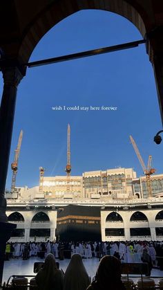 some people are standing in the middle of a building under construction with cranes on top