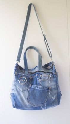 a denim purse hanging on the wall with a leather strap around it's shoulder