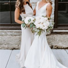 two beautiful women standing next to each other holding bouquets