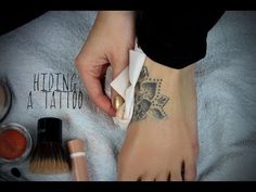 a woman's foot with tattoos on it next to makeup and other cosmetics items