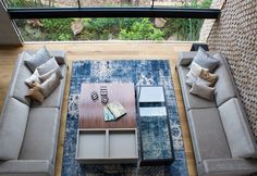 a living room with couches, tables and windows looking out onto the woods outside