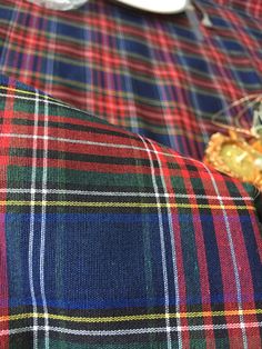 a close up of a plaid table cloth with food on the plate next to it