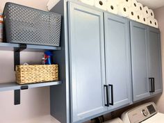 a washer and dryer in a small room with blue cabinets, white walls