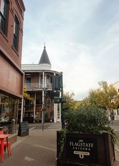 an empty street in front of a building with a clock tower on the corner and a sign that says flagstaff arizona