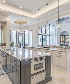 a large kitchen with marble counter tops and an island in front of two windows that look out onto the outdoors