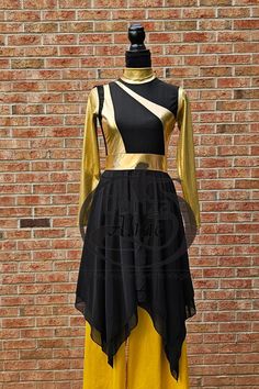 a mannequin wearing a black and yellow dress in front of a brick wall