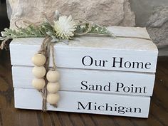 a white box with some wood beads tied to it and the words our home, sand point, michigan