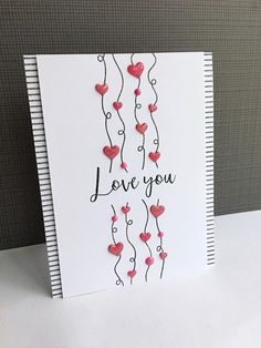 a white card with red hearts and the words love you written on it in black ink