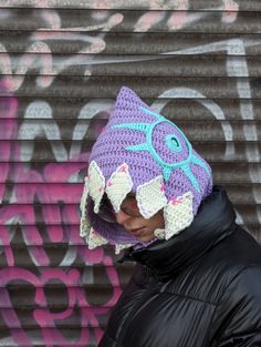 a person wearing a purple crocheted hat with an owl on it