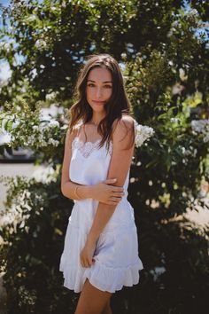 a woman standing in front of a tree with her arms crossed