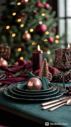 a christmas table setting with candles, plates and napkins