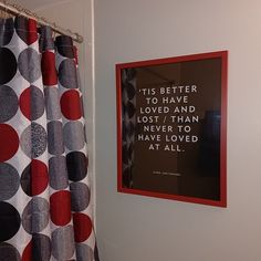 a bathroom with polka dot shower curtain and framed quote