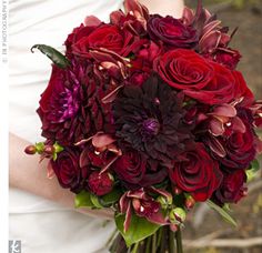 a bride holding a bouquet of red and purple flowers