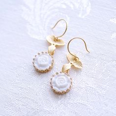 Inspired by nature, these mini flower cabochons and leaves create a pure, feminine and pretty look. They tell a romantic story about moonlight and roses. They pair perfectly from a bridesmaid gown or a cocktail dress to your smart clothes or your T-shirt and jeans. Earrings are made of porcelain flower cabochons; gold-pated brass base; gold-plated silver ear hooks. Material: Handmade porcelain moonlight rose cabochons; Gold-plated brass bases; Gold-plated brass leaves; Gold-plated silver ear hoo Delicate Birth Flower Earrings, Elegant Wedding Earrings With Birth Flower, Formal White Rose Design Jewelry, Formal White Jewelry With Rose Design, Elegant Birth Flower Jewelry, Delicate Pearl White Flower Earrings, Elegant Birth Flower Earrings As A Gift For Her, Elegant Rose Gold Earrings With Birth Flower, Rose Gold Birth Flower Earrings For Wedding