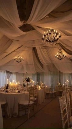 an image of a wedding venue with chandeliers and white drapes on the ceiling